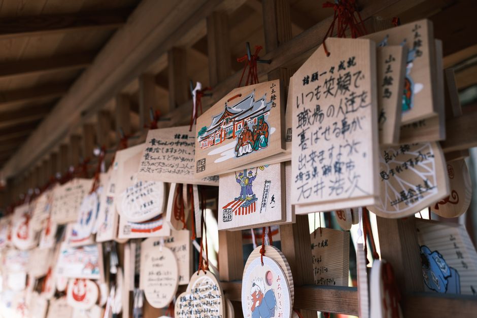 神社で展示されるカラフルな絵馬に書かれた日本語のテキストが、文化的な伝統を捉えています。