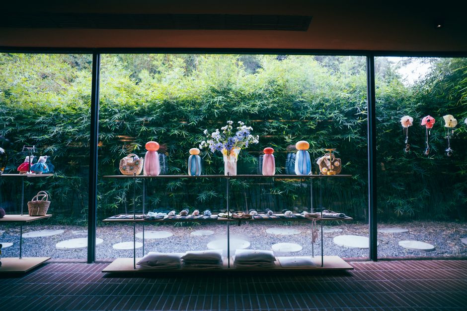 現代的な店内に、緑豊かな竹を背景に、美しいガラス工芸品や装飾品が展示されている。