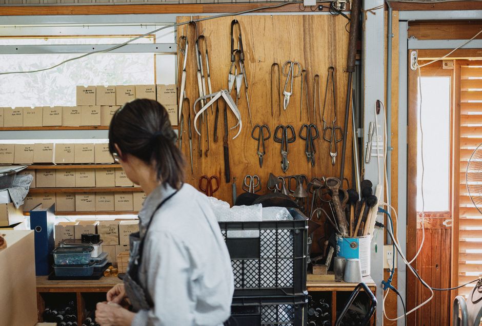 日本の長野にある伝統的な工房で、道具や材料に囲まれながら作業する職人。