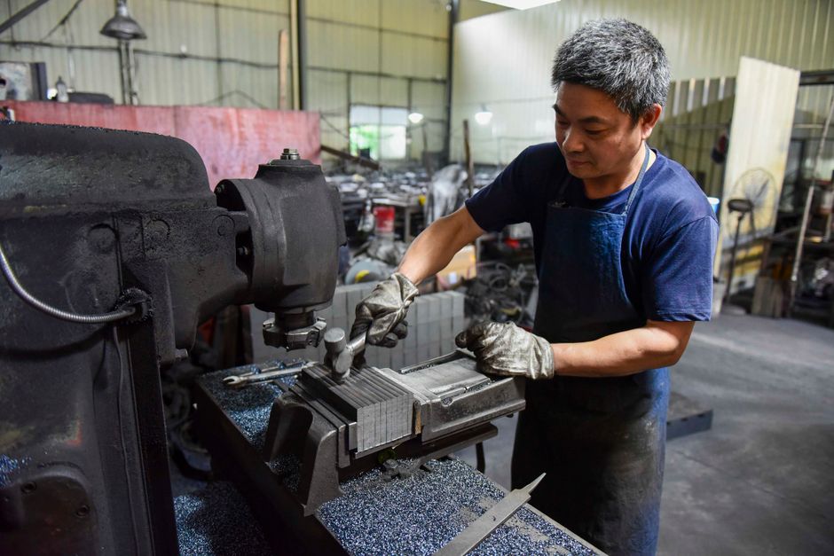 精密に機械を操作しながら工業用ワークショップで働くアジア人男性。