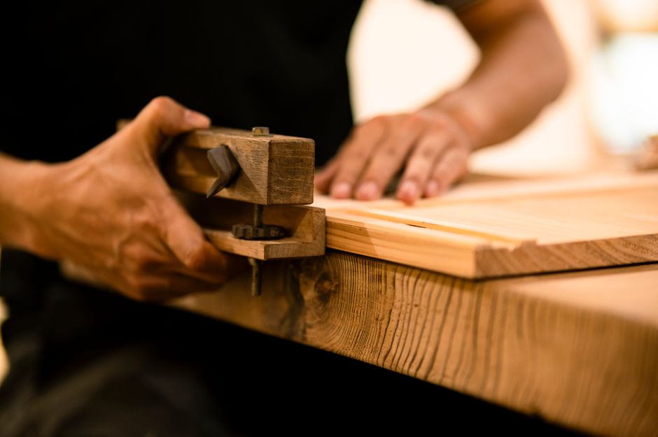 ワークショップで手工具を使って木材を加工する熟練の大工。職人技と精度を示しています。