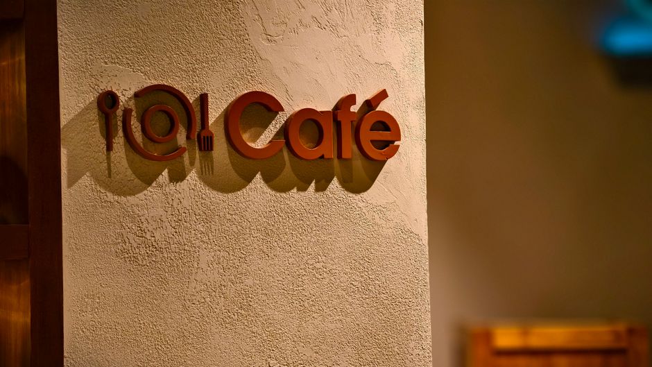 温かみのある照明が質感のある壁に影を落としているスタイリッシュなカフェの看板のクローズアップ。